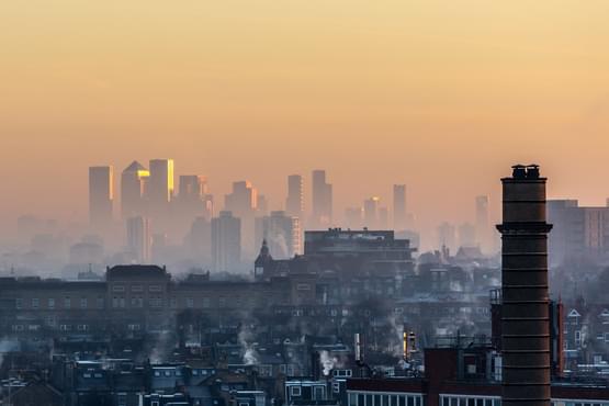 A foggy city landscape of chimneys and high rise buildings