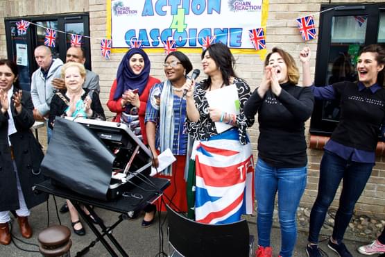 Group of people stood in a line, one with a microphone and a union jack flag