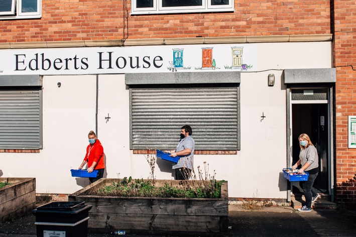 picture for projectStory: Three people carry food parcels outside Edberts House building