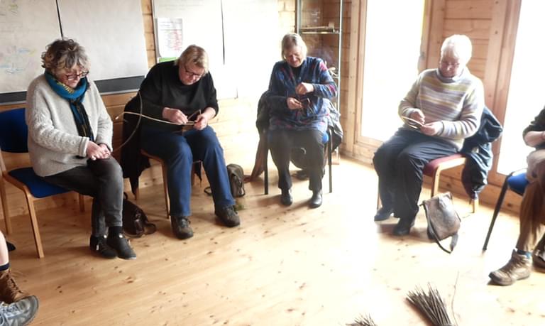 Older residents sit in a circle knitting